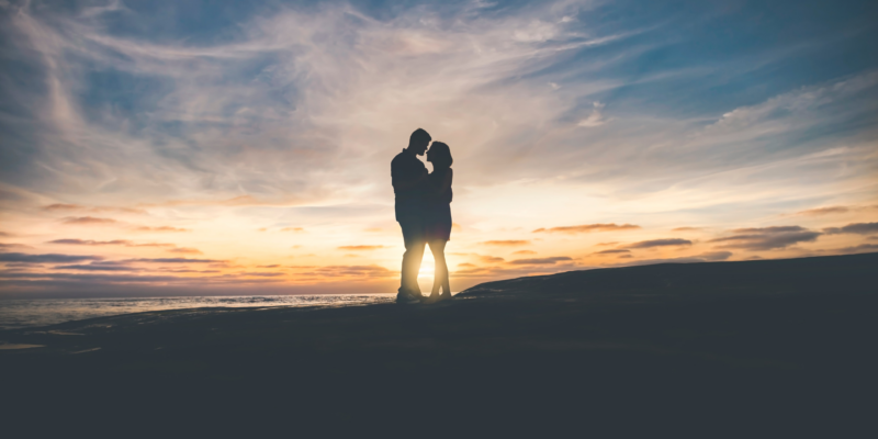 Couple embracing on the beach at sunset.